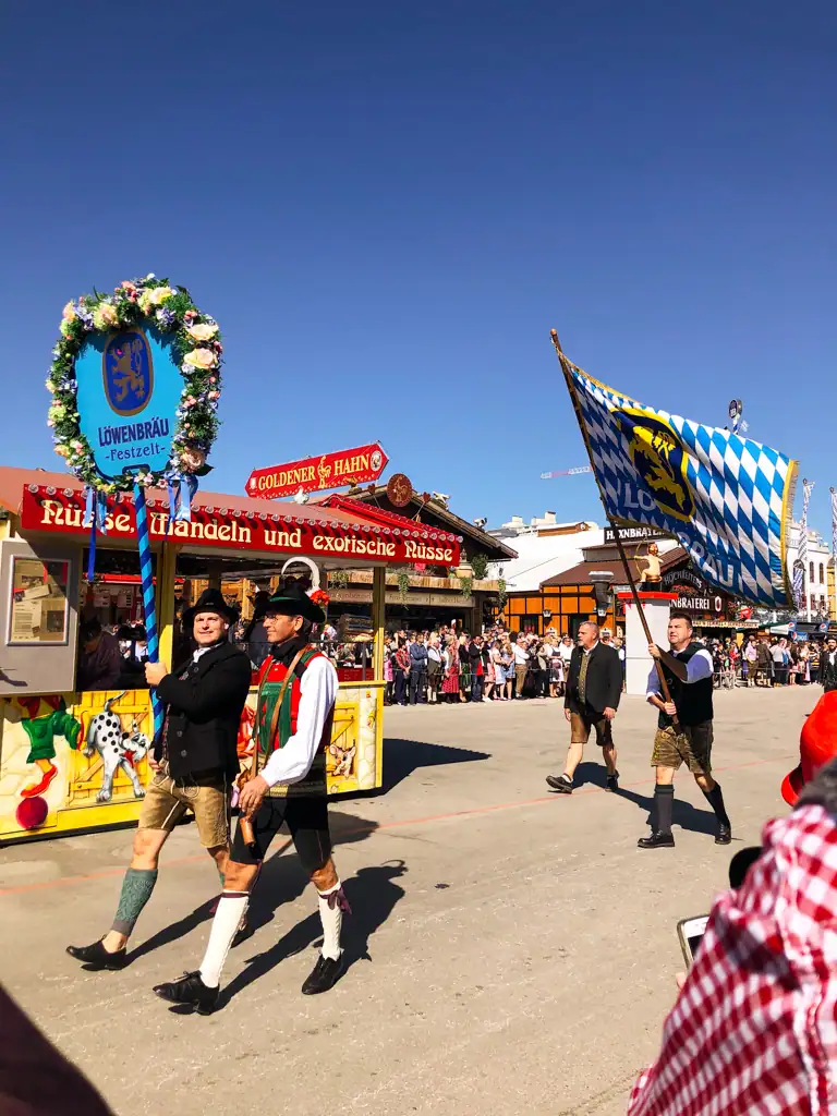 the oktoberfest parade with traditional dressed men holding and waving flags. 