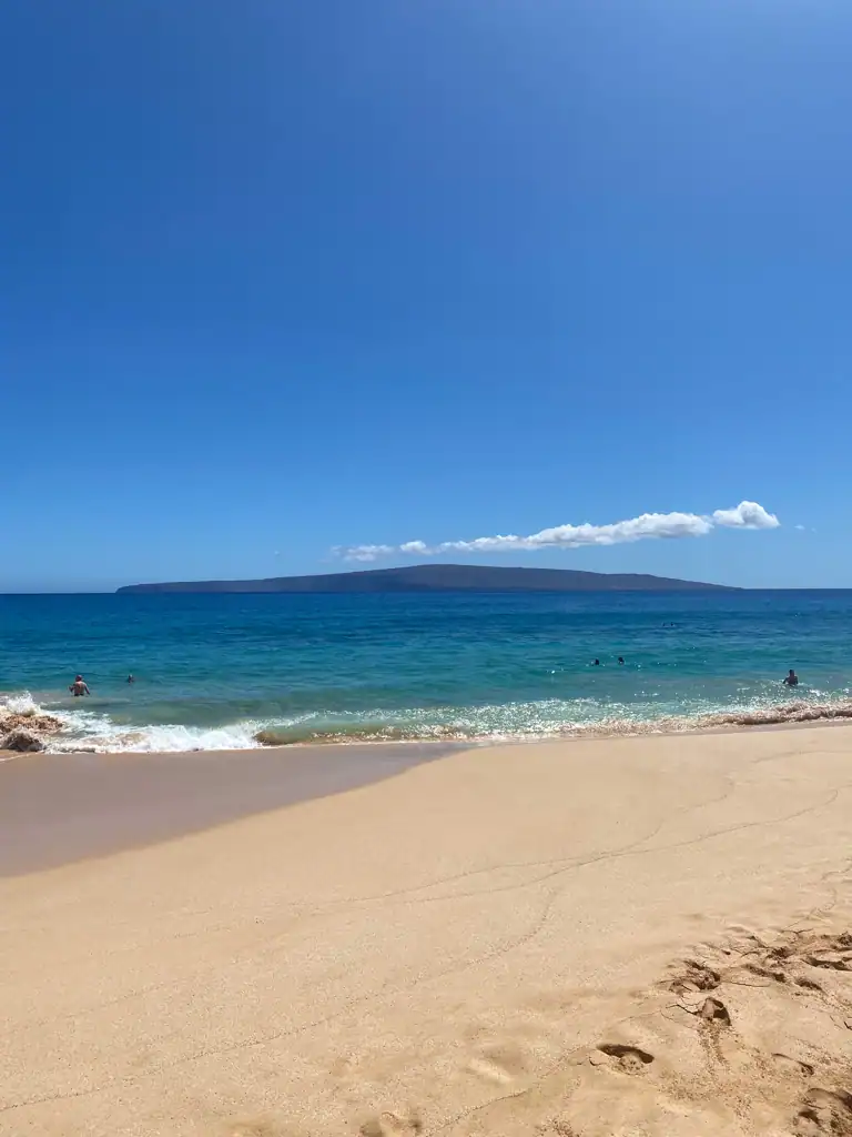 Large beach expanse with scattered people at one of the 5 amazing beaches in Maui. 