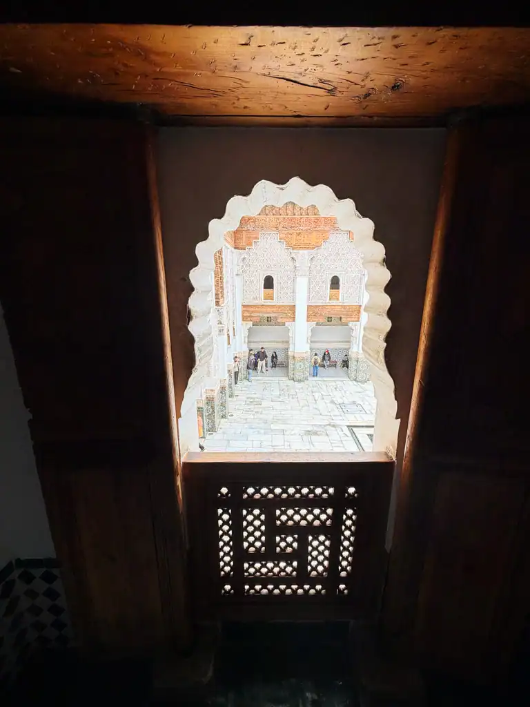 looking out through an ornate doorway to the courtyard of the ben youssef madrasa. 