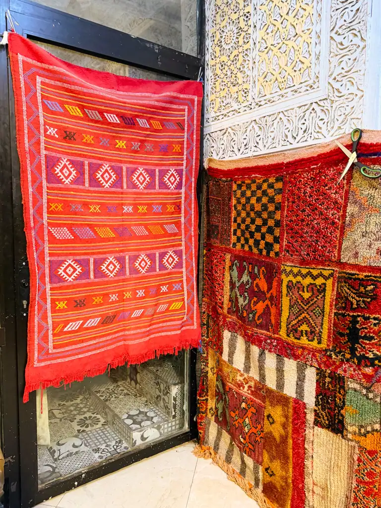 red patterned rugs hang on walls in morocco.