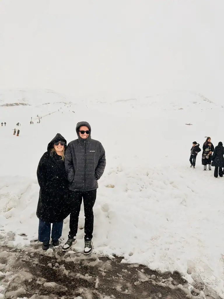 two people wearing all black and sunglasses stand in the snow in this morocco travel guide.