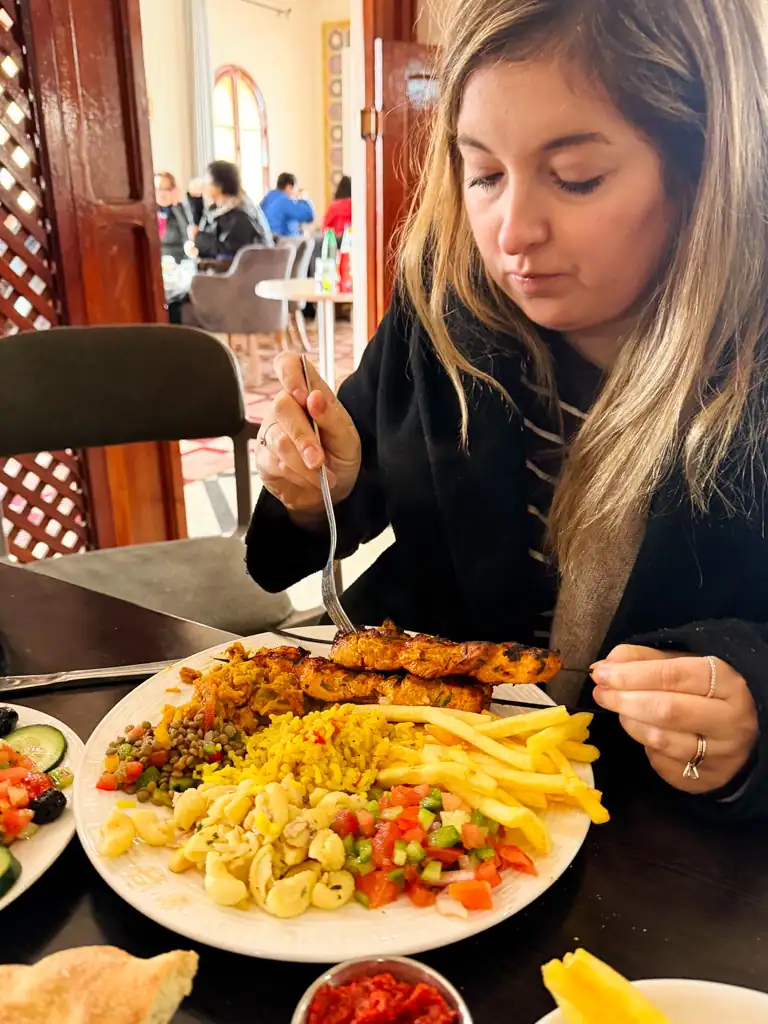 a girl eats chicken, fries and tomatoe salad.