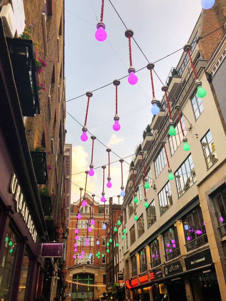 the purple and green lights above a street in Carnaby.