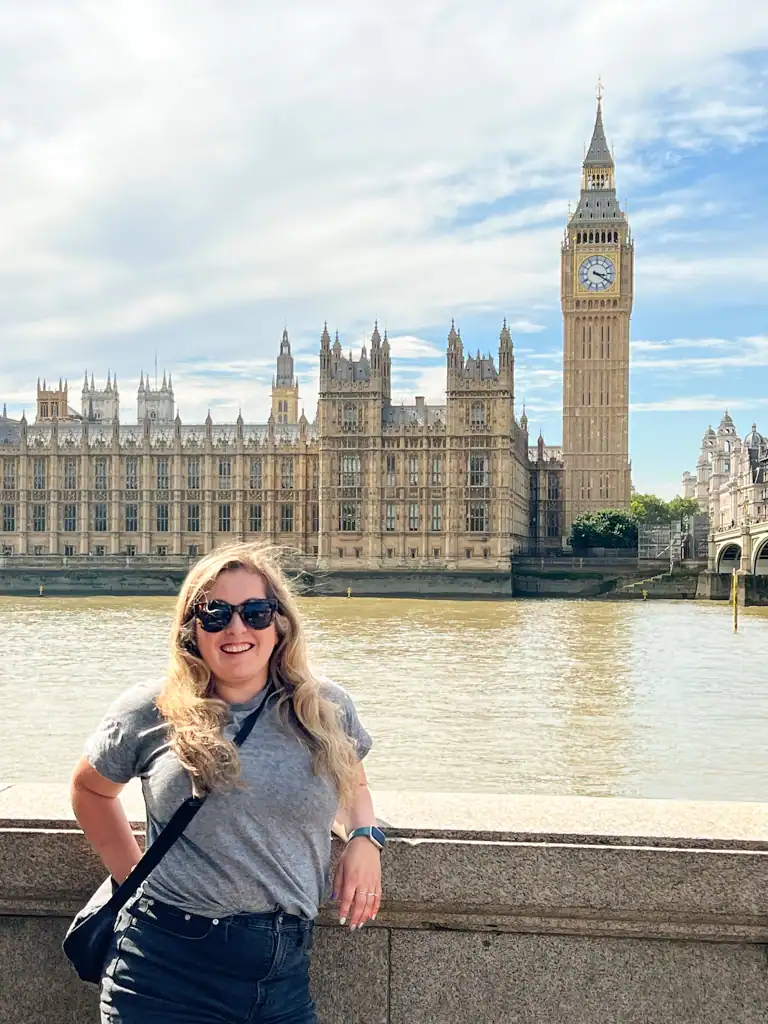 A girl stands in front of a view of Big Ben and the parliament building. 