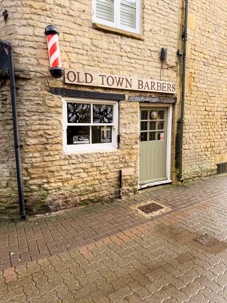 a golden brick building titled old town barbers with a light green door. 