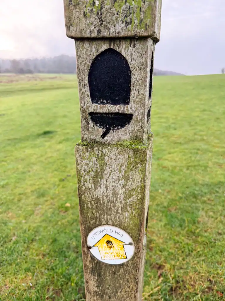 a wooden post with a Cotswolds Way logo. 