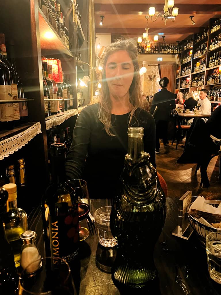 A girl with wine bottles and mood lighting at Carmelo in Lyon.