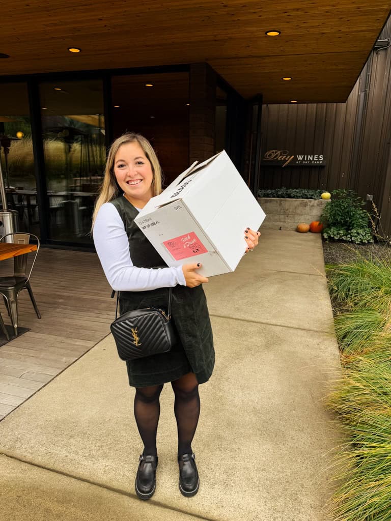 a girl holds a box of wine in the willamette valley.