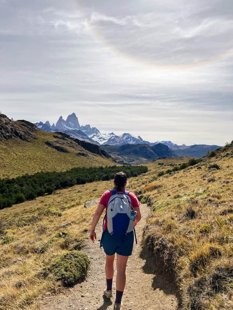 a girl walking in the mountains with a backpack for the patagonia w-trek packing list 