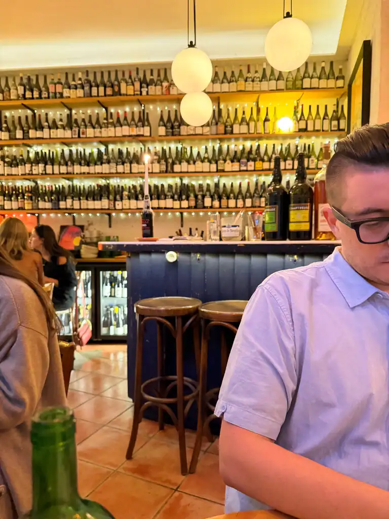 partial figure of a man with a large bar of wine in the background. 