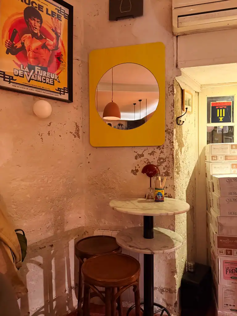 the corner of a wine bar with white walls a a kung fu poster. 