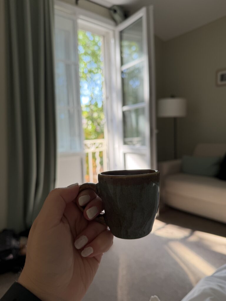 a cup held by a hand with a balcony in the background. 