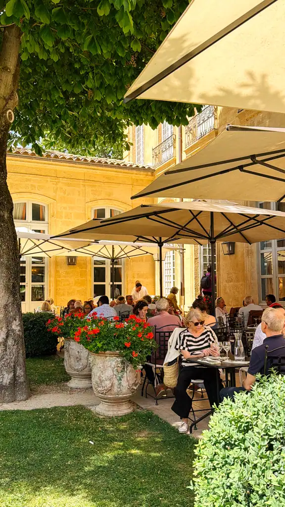 the courtyard and gardens of people having lunch on the weekend in aix-en-provence. 