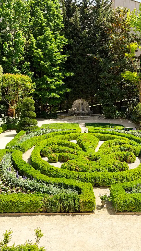 the gardens of hotel de caumont in a weekend in aix-en-provence. With a fountain in the back and a fleur de lis made of hedges. 