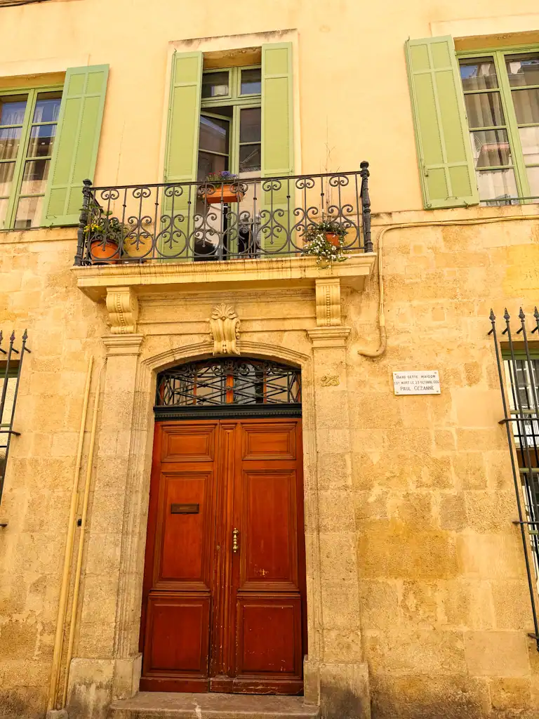 a building in Aix-en-provence with green shutters, a wood door and beautiful golden stone. 