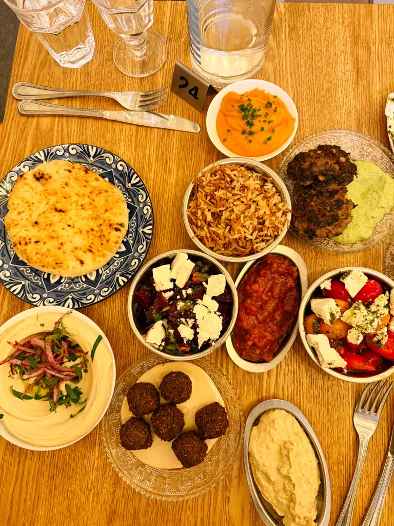 a smattering of mediterranean food on different plates placed on top of a table. 
