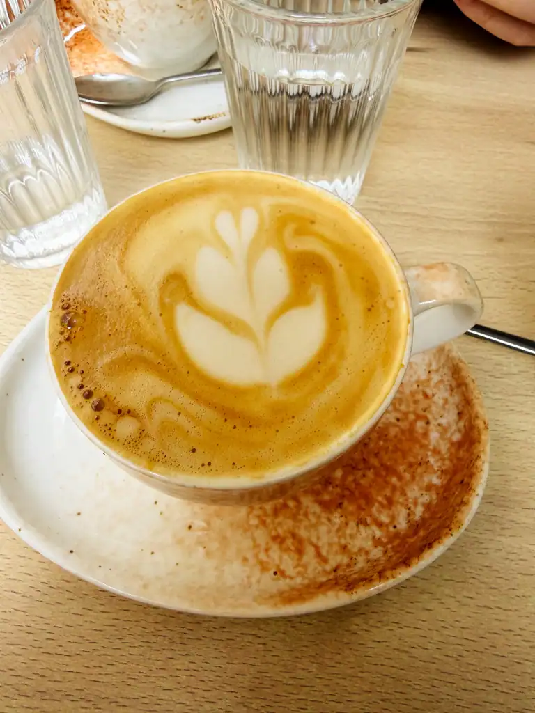 a close up of a latte with a flower milk art. 